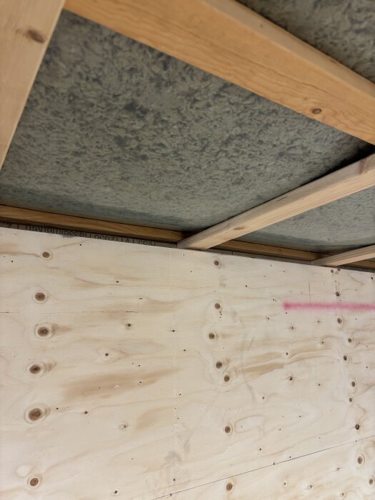 Ytterväggskonstruktion med träreglar och plywood, visar installationsutrymme för isolering längs takets undersida.