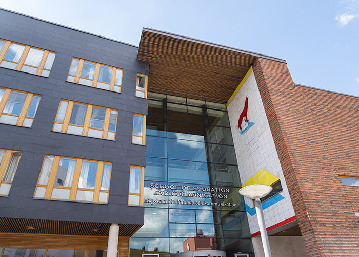 Byggnad vid Jönköpings högskola i tegel och glas med färgrikt konstverk vid huvudingången.