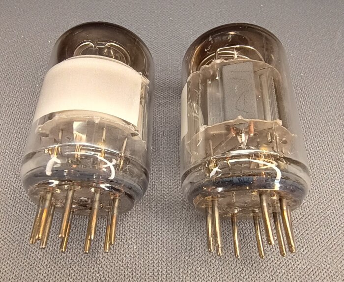 Två indikatorrör EAM86 för bandspelare från 1960-talet, känd som "magiska ögon", placerade på en grå bakgrund.