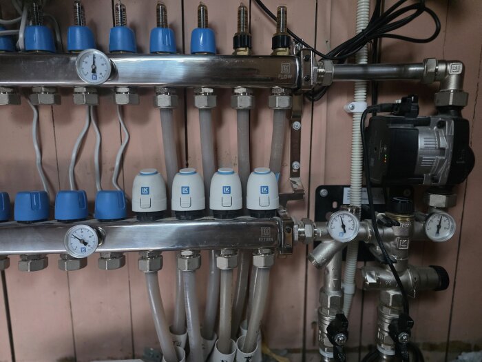 LK fördelare med shunt VS2 och tryckmätare, fjärrvärmesystem, flödes- och returventiler, regulatorer, rörkopplingar och anslutningar monterade mot vägg.