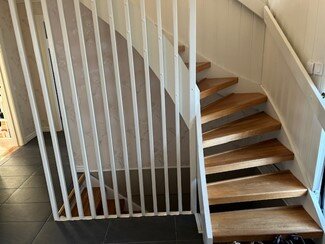 Trappa från 70-talet med eksteg, vitmålat räcke och vagnstycke, sett från hall med mörkt golv. Letar moderniseringslösningar.