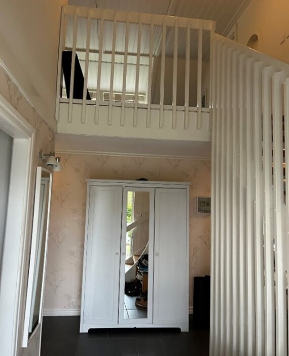 Vitmålad sjuttiotalsräcke vid trappa och hall med vit garderob och spegeldörrar.