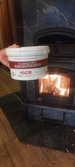 Hink med eldfast reparationsmassa framför en brinnande kamin.