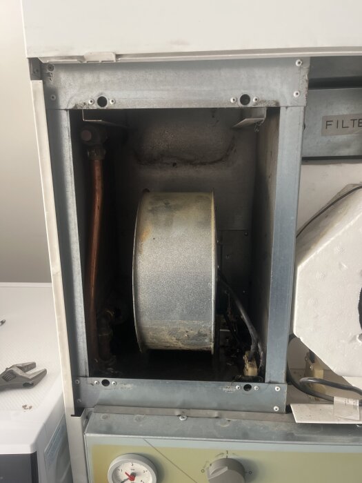 Inre del av en maskin med synliga rör och fläkt, eventuellt en värmepump som läcker vatten i övre vänstra hörnet.