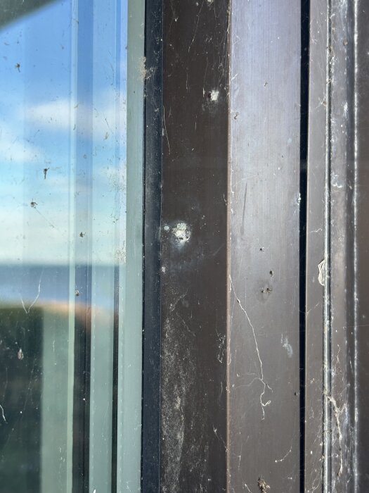 Fönsterkarm med avbruten popnit intill fönsterglaset och yta med viss smuts och repor.