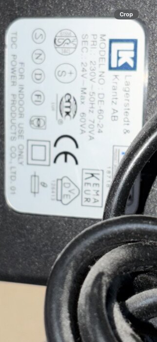 Etikett på elektronisk enhet, produktmodell DE-60-24 från Lagerstedt & Krantz AB, med information om spänning och säkerhetsmärkningar.