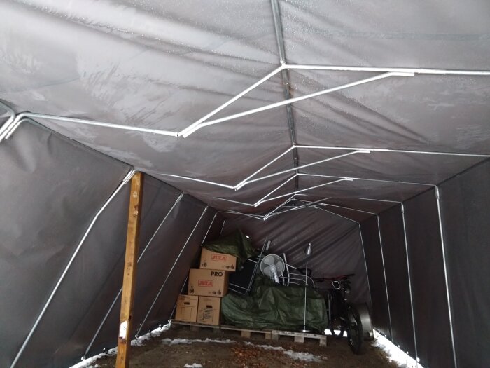 Garagetält med böjda takstolar från tyngden av snö, kartonger och utrustning under en nedsjunken tältduk, inlägg diskuterar möjliga lösningar.