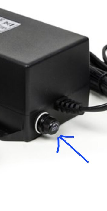 Säkringshållare på sidan av elektrisk enhet markerad med blå pil.