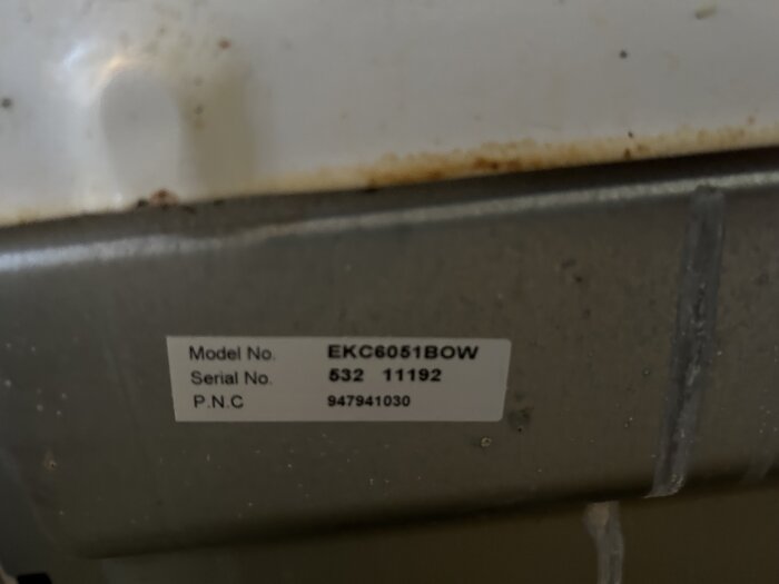 Etikett på baksidan av en spis med modellnummer EKC6051BOW och serienummer 53211192; relevant för elanslutning.