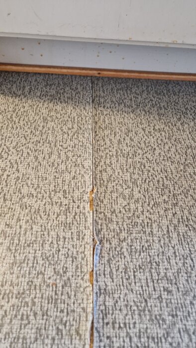 Sprucket golv från 1968 med synlig skarv. Möjligt linoleum, diskussion om reparation och eventuell asbestrisk.