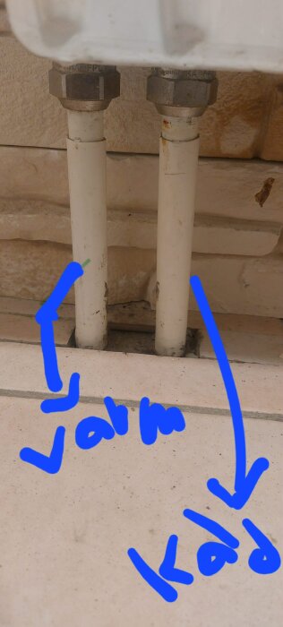 Två rör med etiketter för varm och kall vattenledning, markerade med blå text och pilar.