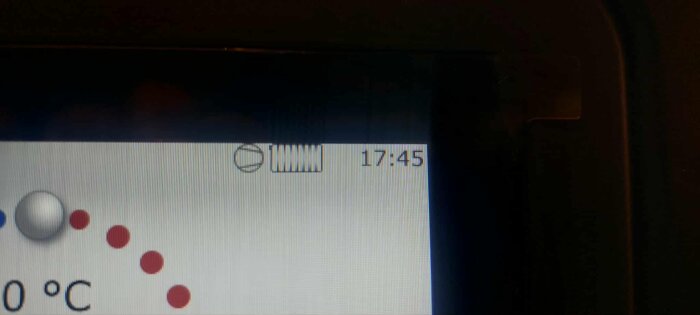 Display som visar temperaturkontroll, klockan 17:45, med röd punkt och vit knapp på en kurva.