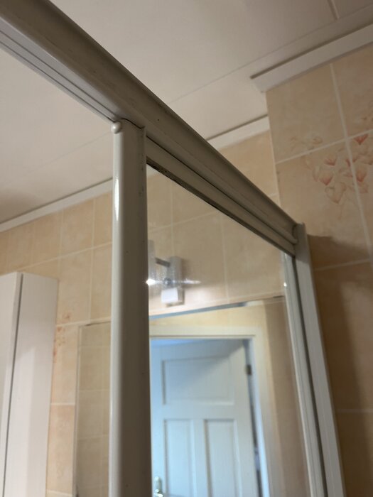 Duschrumsdetalj visar spåret i väggen där duschväggen har lossnat, med beige kakelvägg i bakgrunden.