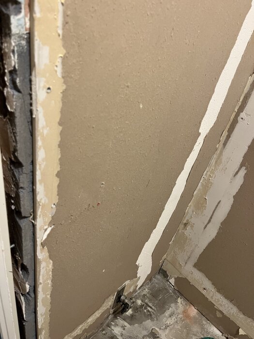 Gipsväggar i ett badrum utan plastmatta, med synliga kanter och gammal fästning, redo för renovering med nytt tätskikt och klinker.