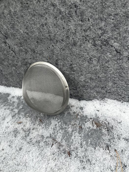 Rostfri sil utan handtag placerad mot betongyta med frost.