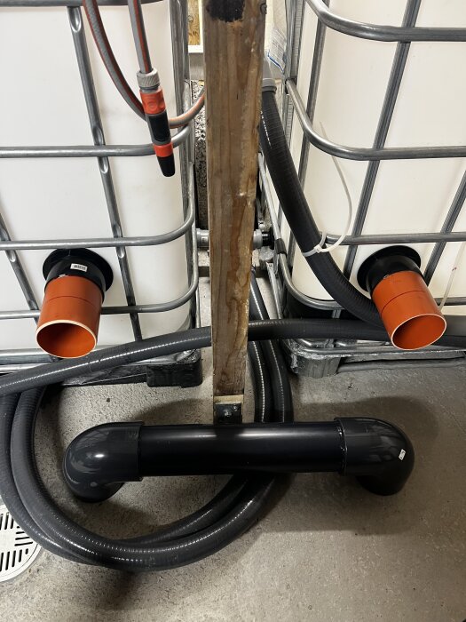 Balanstank med orange och svarta rörkopplingar 110mm för utjämning, två vita tankar och svarta slangar syns tydligt.