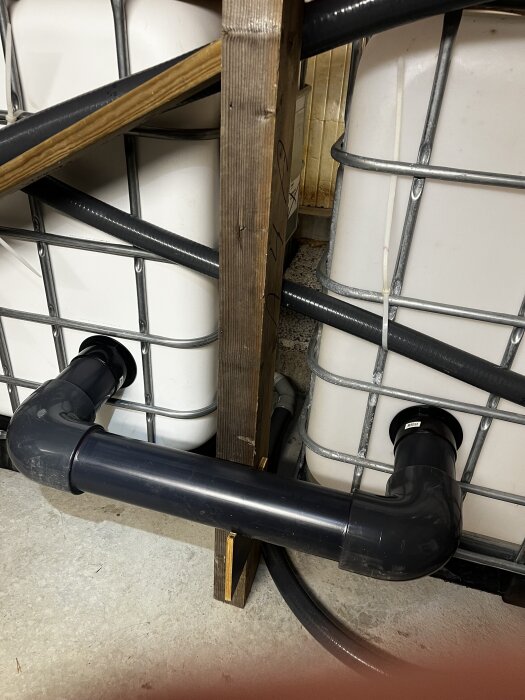 Två stora balanstankar med ett 110 mm rör emellan för utjämning, placerade på ett golv med trästöd och omgivande kablar.