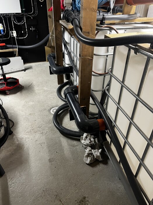 Bilden visar två balanstankar med stora svarta rör (110 mm) mellan dem för att underlätta snabb vätskeutjämning, placerade på ett betonggolv i ett byggnadstekniskt utrymme.