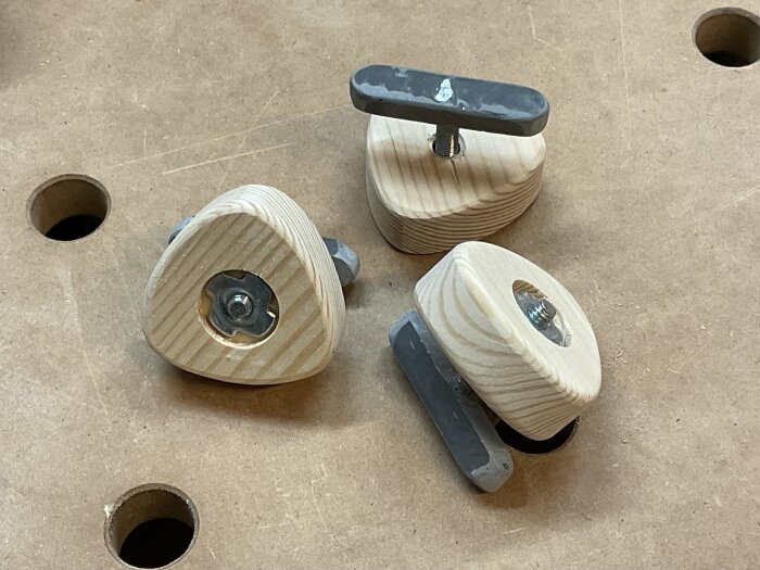 Trädetaljer och metallkomponenter på en arbetsbänk, troligen delar av ett monteringsprojekt med M6-skruvar och epoxi.