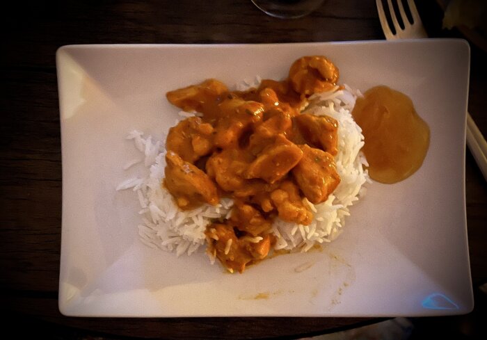 Tikkamasala med kyckling och blomkål på ris med mango chutney på tallrik.