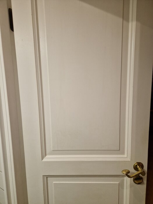 Vit spegeldörr med metallhandtag, en del av ett byggprojekt för att måla om innerdörrar från 70-talet i syfte att uppnå en slät finish.