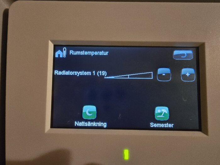 Skärm på värmepumpens kontrollpanel som visar rumstemperaturen och radiatorsysteminställningar, med knappar för natt- och semesterläge.