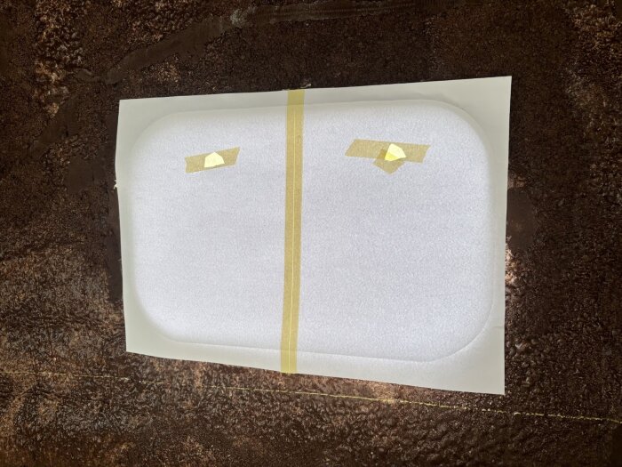 Pappersmall för fönsterkarm tejpad på mörk yta, mall används för att snickra träfönsterram i bastustil.