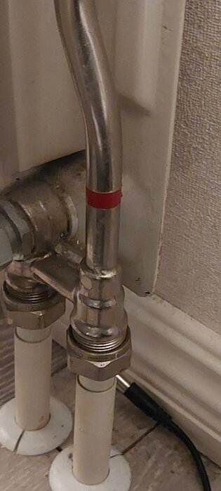 Bild av ett kopparrör med en röd markering, kanske del av ett ettrörssystem, anslutet till ett element i en renoveringssituation.