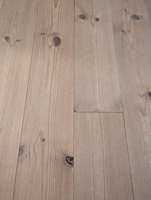 Obehandlat trägolv med synliga kvistar och ådring.