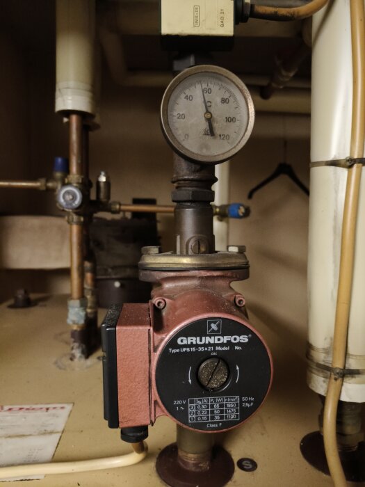 Cirkulationspump från Grundfos ovanför panna, med tryckmätare och omgivande rörsystem.