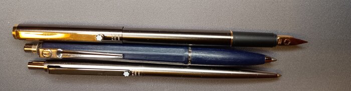 Tre pennor ligger bredvid varandra; en bläckpenna är i mitten, inlägget nämner den som den bättre men mindre praktiska för att skriva.