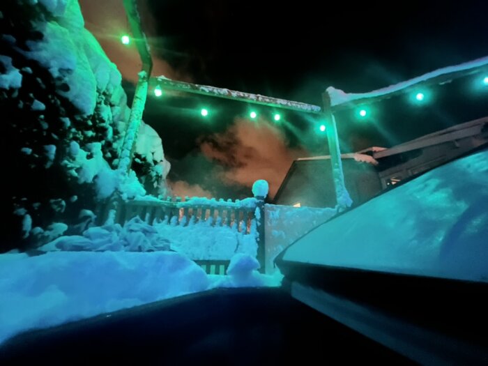 Bubbelpool utomhus omgiven av snö, med gröna ljusslingor i mörkret.