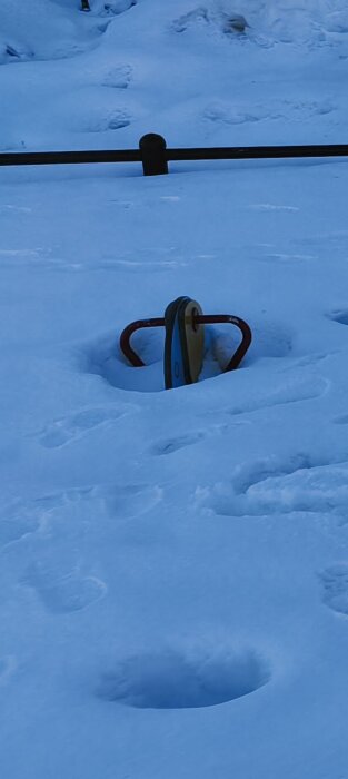 Lekutrustning delvis täckt av snö på en lekplats.