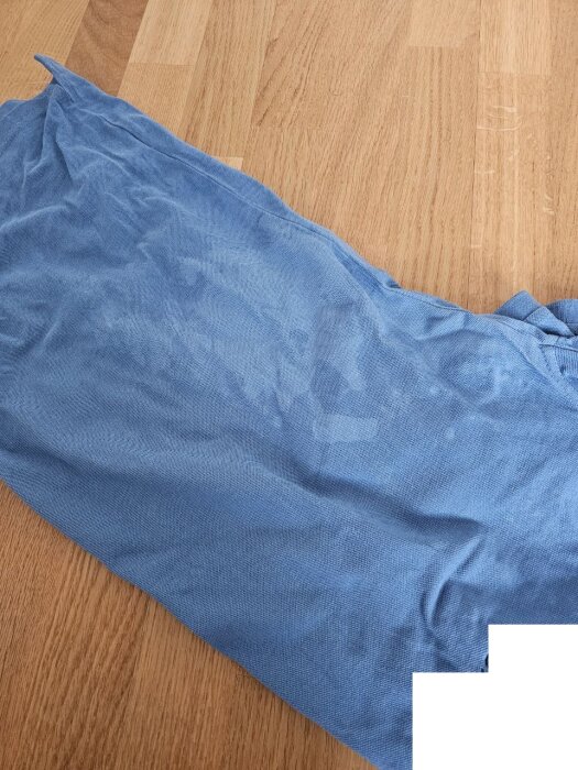 Blå tygbit med vita fläckar på trägolv.