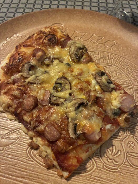 Hemmagjord pizza med korv, svamp, lök, kapris och ost på trätallrik.