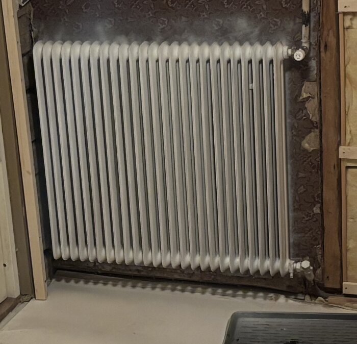 Sista radiatorn i en värmeslinga med tillopp uppe och retur nedan. Installationen är inomhus i ett renoveringsprojekt.