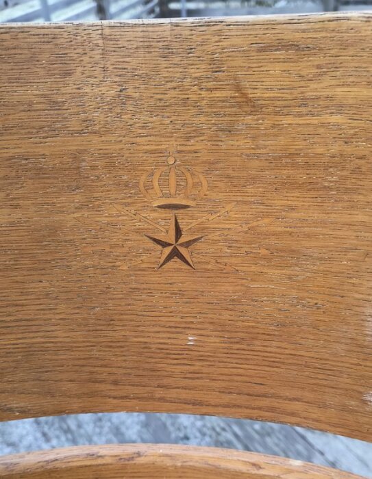 Trärygg på en stol med Televerkets emblem ingraverat, visar en krona och stjärna.