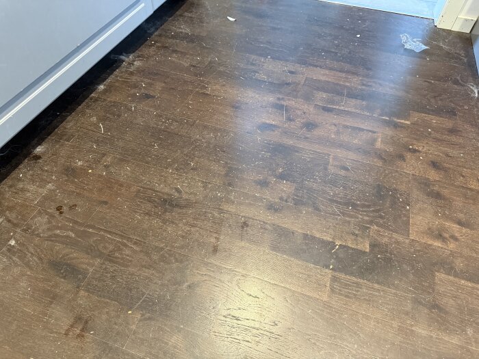 Repor och märken på mörkt trägolv i kök, efter att ha blivit trampade med dubbade skor.