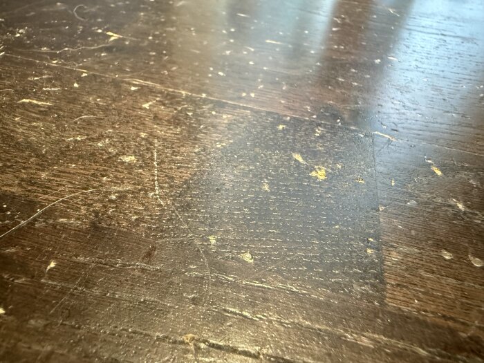 Repor och märken i ett mörkt trägolv.