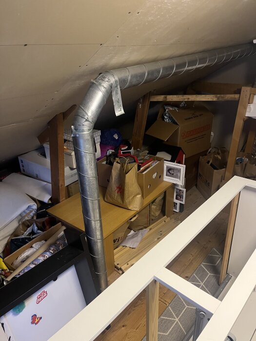 Ventilationskanal i ett förråd med lådor och föremål staplade runt omkring.