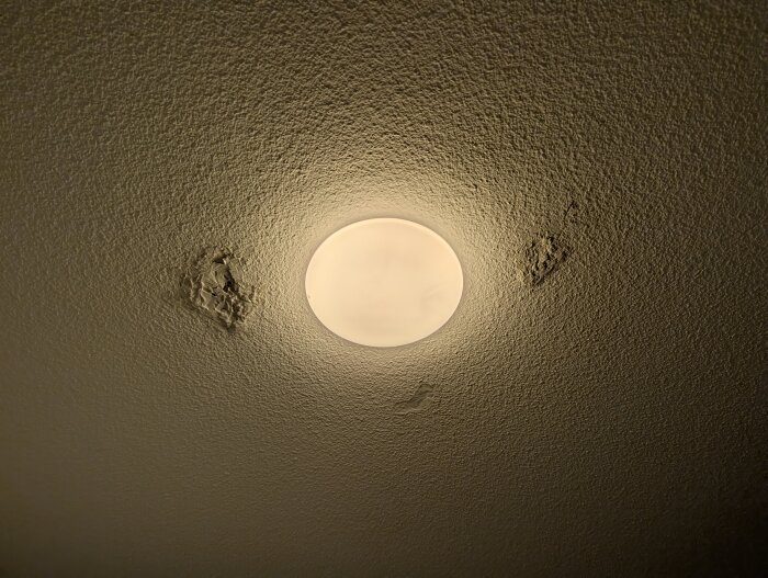 Tak med en rund lampa, spår av spacklade områden syns runtom.