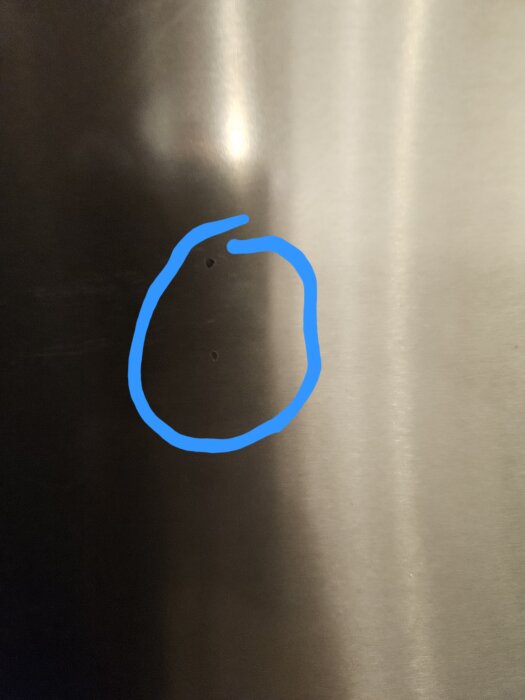 Två små märken på kylskåpets yta, inringade med blått, orsakat av dörr som slagits mot mikrovågens handtag.