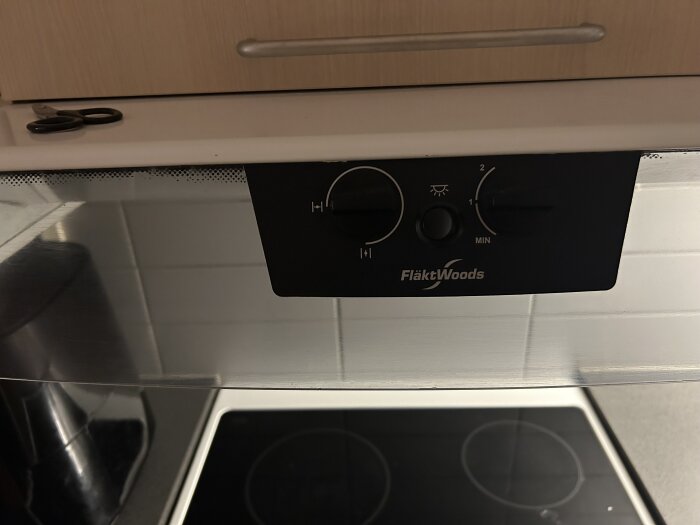 FläktWoods ventilationspanel med reglage för fläkthastighet och potentiell forcering, installerad ovanför spis i kök.