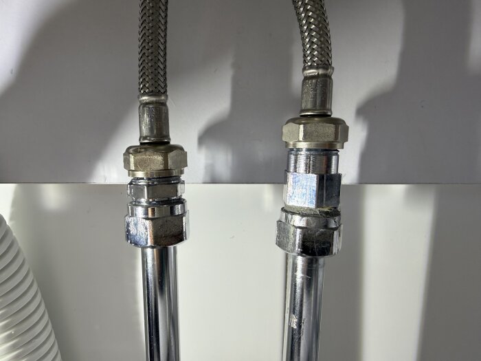 Två metallrör med kopplingar och flätade slangar, monterade och åtdragna. Inlägg nämner användning av lin och rörkit samt synlig pasta/fett på kopplingar.