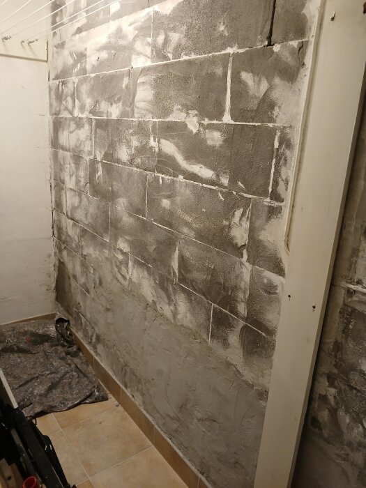 Rå betongvägg under renovering med spackel och synliga fogar, del av ett projekt för att hitta hantverkare för putsning i Göteborg.