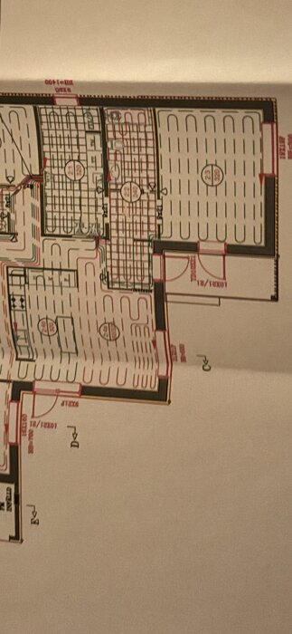 Planskiss över golvvärmesystem med uppdelade slingor, olika zoner markerade. Visar distribution och layout av vattenburen värme i olika rum.