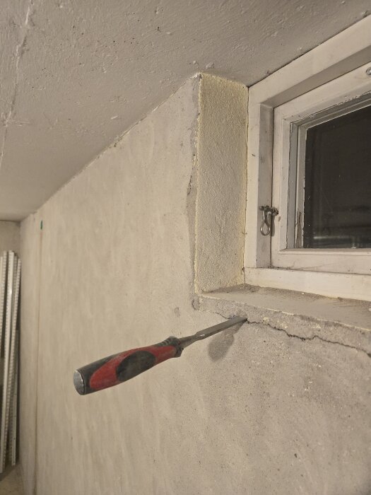 Stämjärn som används för att ta bort murbruk runt ett uttorkat och krackelerat fönster, förbereder inför renovering.