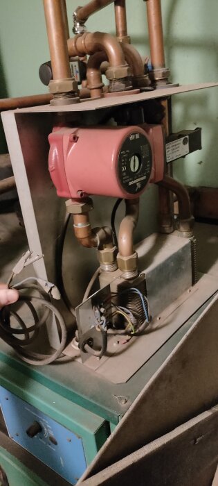 Rörsystem och komponenter för pelletspanna med synliga kablar och anslutningar i ett maskinrum.