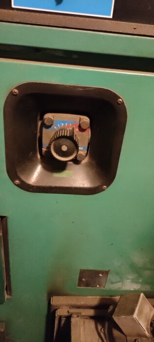 Kontrollpanel på en pelletspanna med en ratt för inställning, omgiven av en svart ram. Ytan är grön och något rödmilerad.