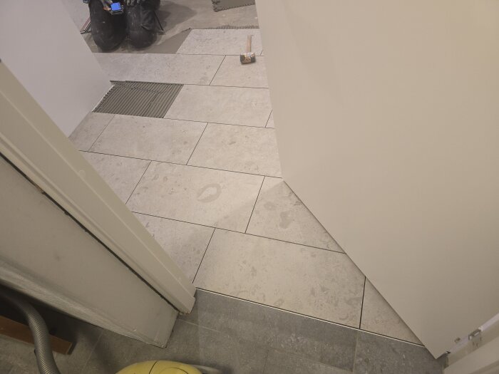 Nylagt klinkergolv i en ljus korridor med övergång till ett rum med annan golvnivå; en man sitter på golvet i bakgrunden.